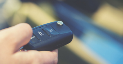 Person clicking button on a vehicle key remote.