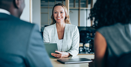 Image of a woman sitting at a desk talking to a couple